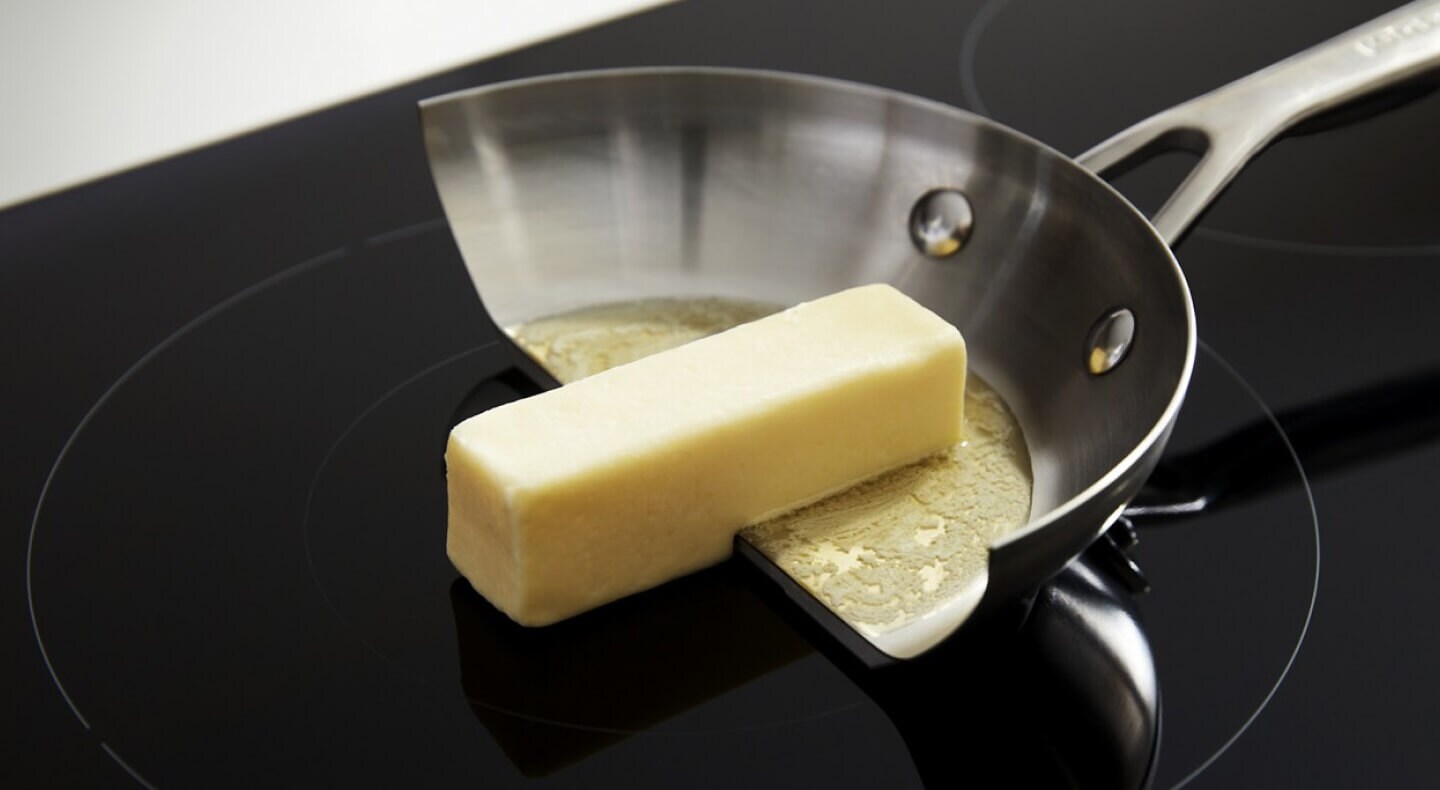 A pan cut in half to demonstrate that butter melts in the pan but not on the induction element