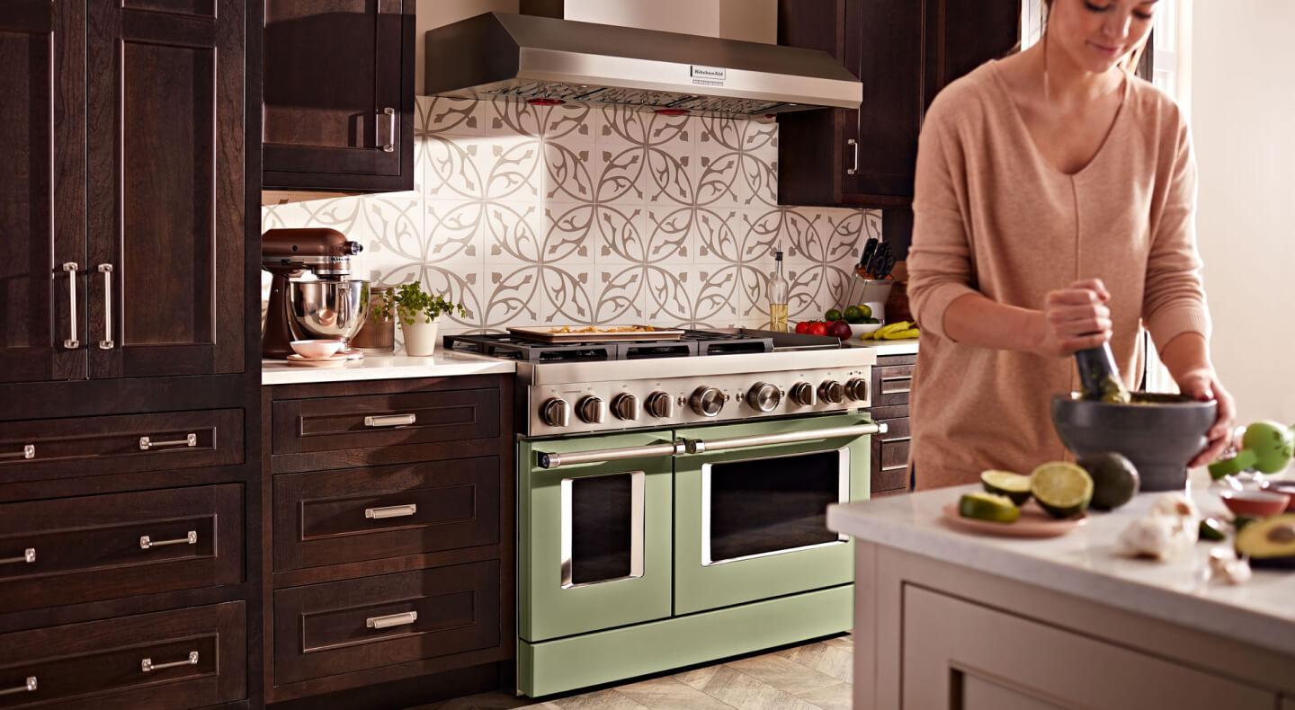 KitchenAid® range set in cabinetry behind person preparing food at an island KitchenAid® range set in cabinetry behind person preparing food at an island