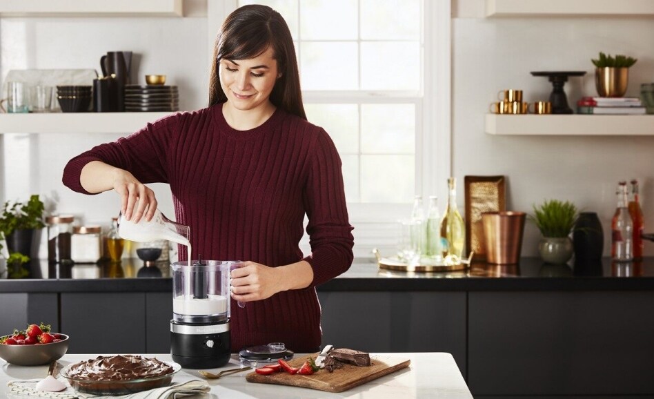 Smiling person pouring cream into a cordless food chopper Smiling person pouring cream into a cordless food chopper