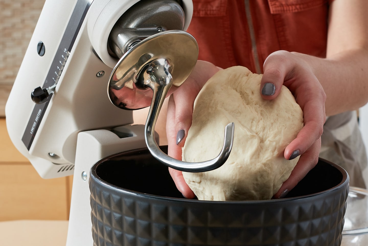 Woman removing a ball of dough from a KitchenAid® stand mixer Woman removing a ball of dough from a KitchenAid® stand mixer