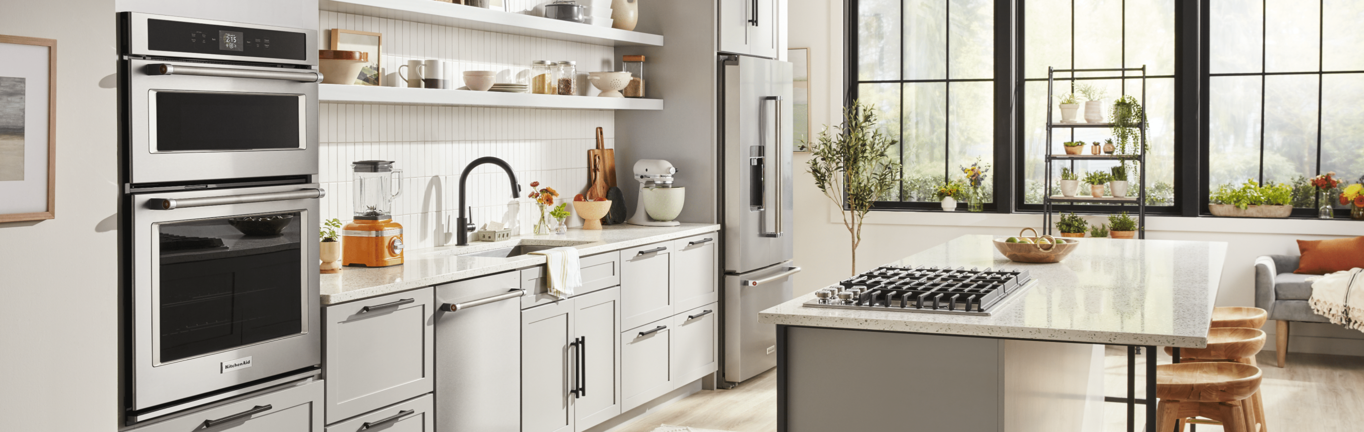 Kitchen with pale gray cabinets, white backsplash, stainless appliances.