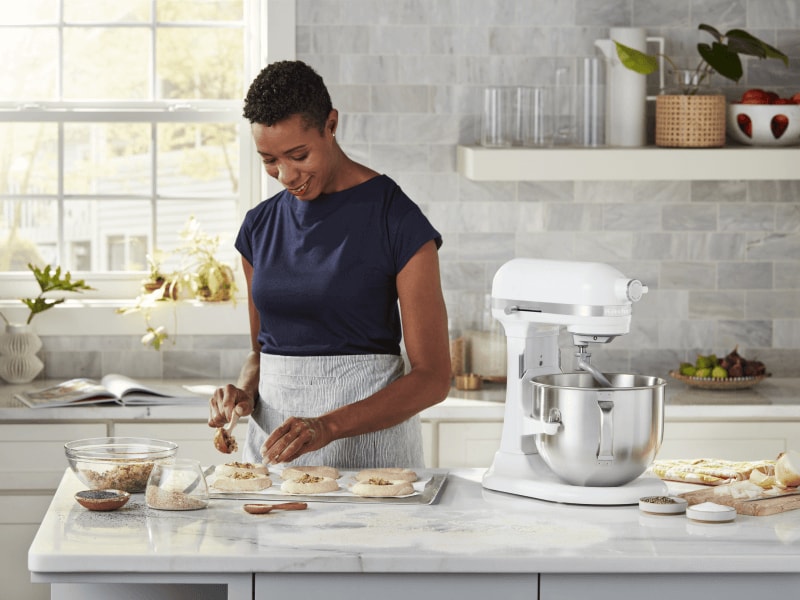 Woman baking at white marble countertop with white stand mixer