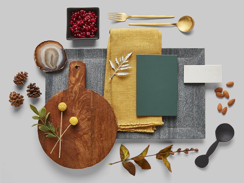 Accessories that look nice in a neutral-toned kitchen, including a wooden cutting board and mustard-colored cloth napkin