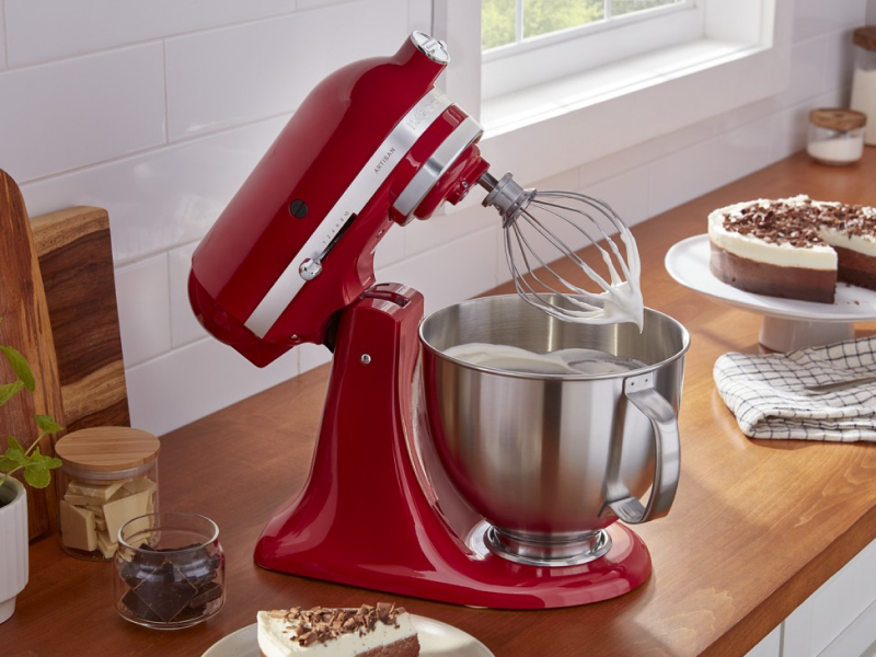 Red KitchenAid® stand mixer whipping cream next to pie on counter Red KitchenAid® stand mixer whipping cream next to pie on counter