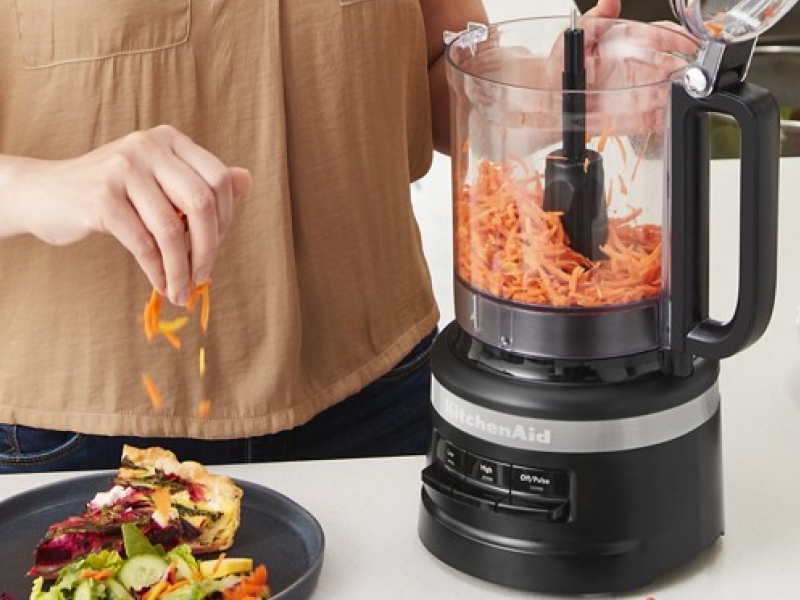 Person shredding carrots in a black food processor Person shredding carrots in a black food processor