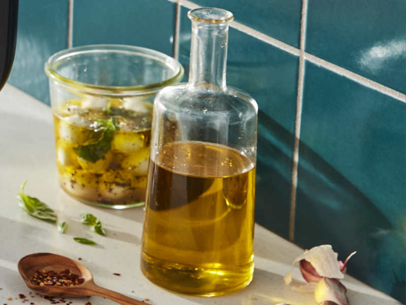 Bottle of olive oil next to a glass jar of marinated mozzarella