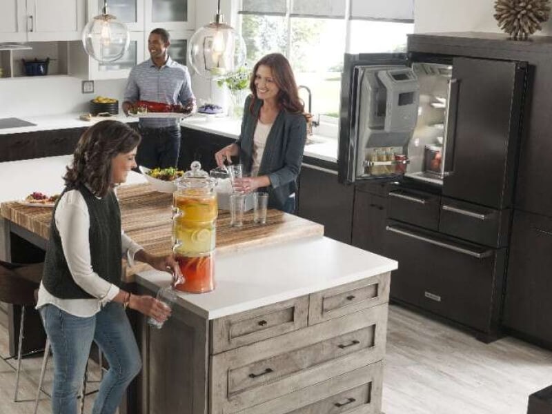 People gathering and cooking in a kitchen with a KitchenAid® 4-door refrigerator People gathering and cooking in a kitchen with a KitchenAid® 4-door refrigerator