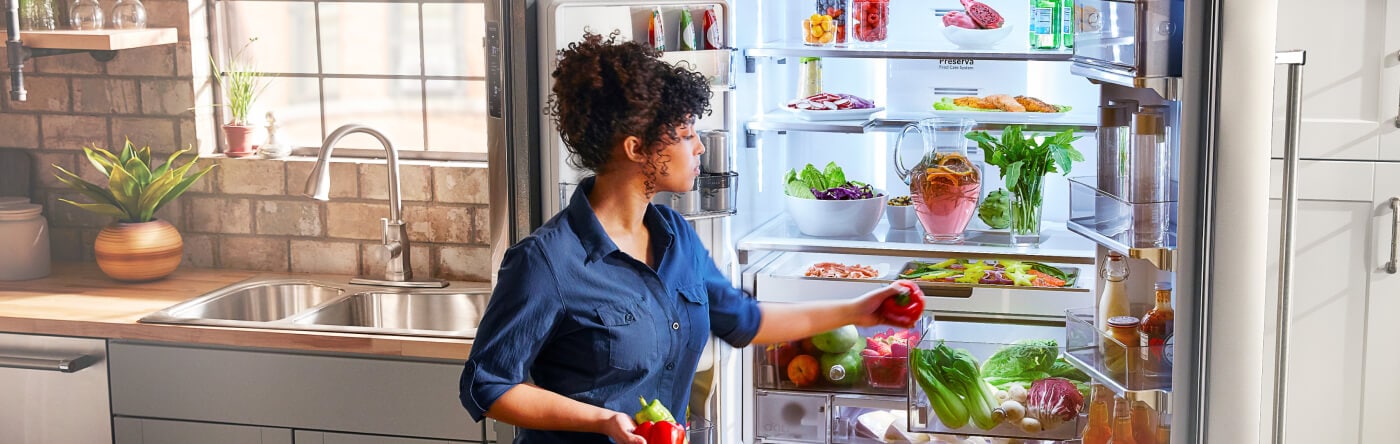 Person loading bell peppers into the crisper drawer of a refrigerator