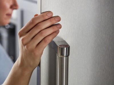 Person touching a stainless steel refrigerator door