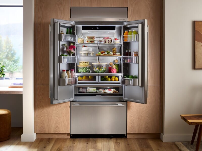 Open KitchenAid® French door refrigerator built into brown cabinetry