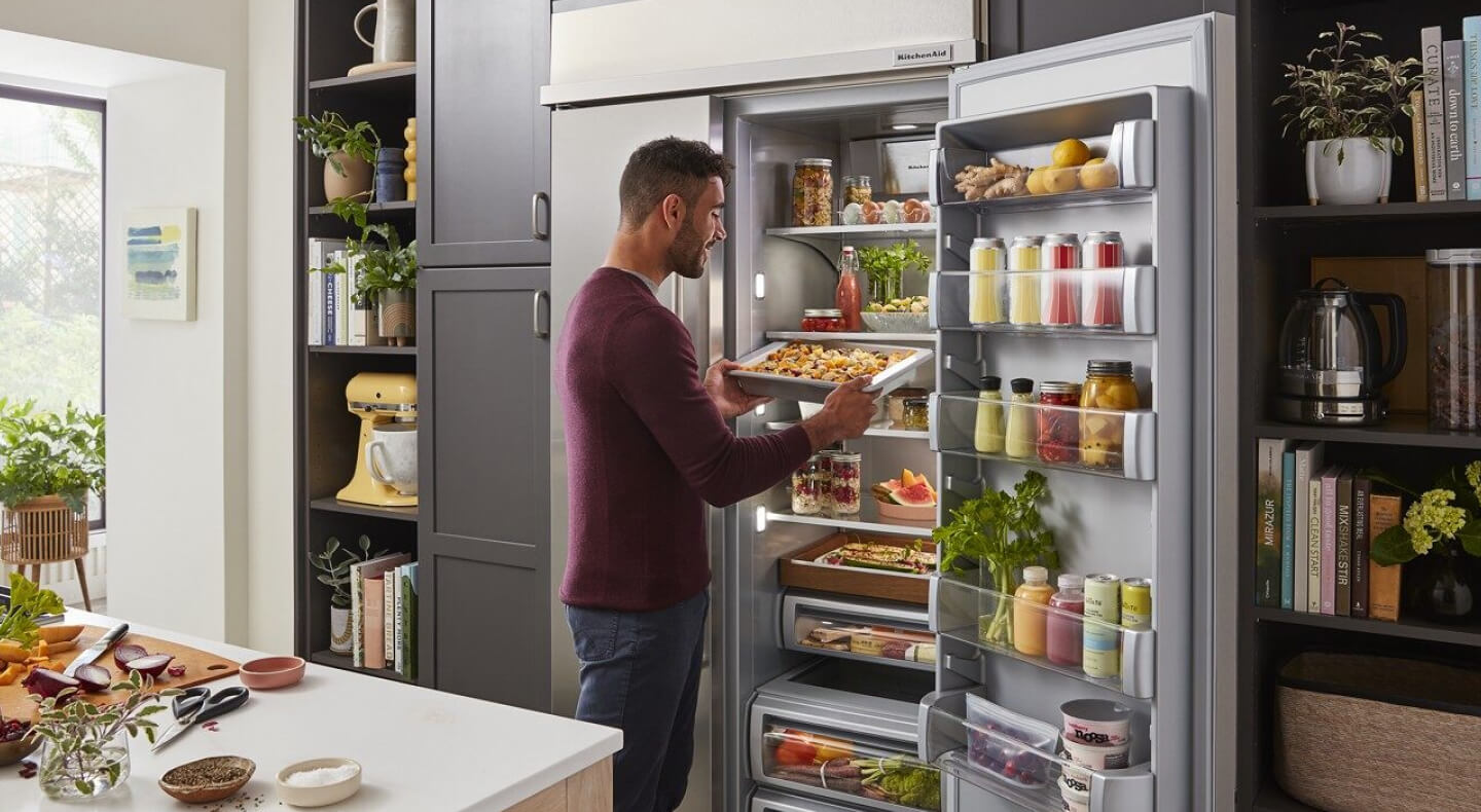 Person removing food from a side-by-side refrigerator