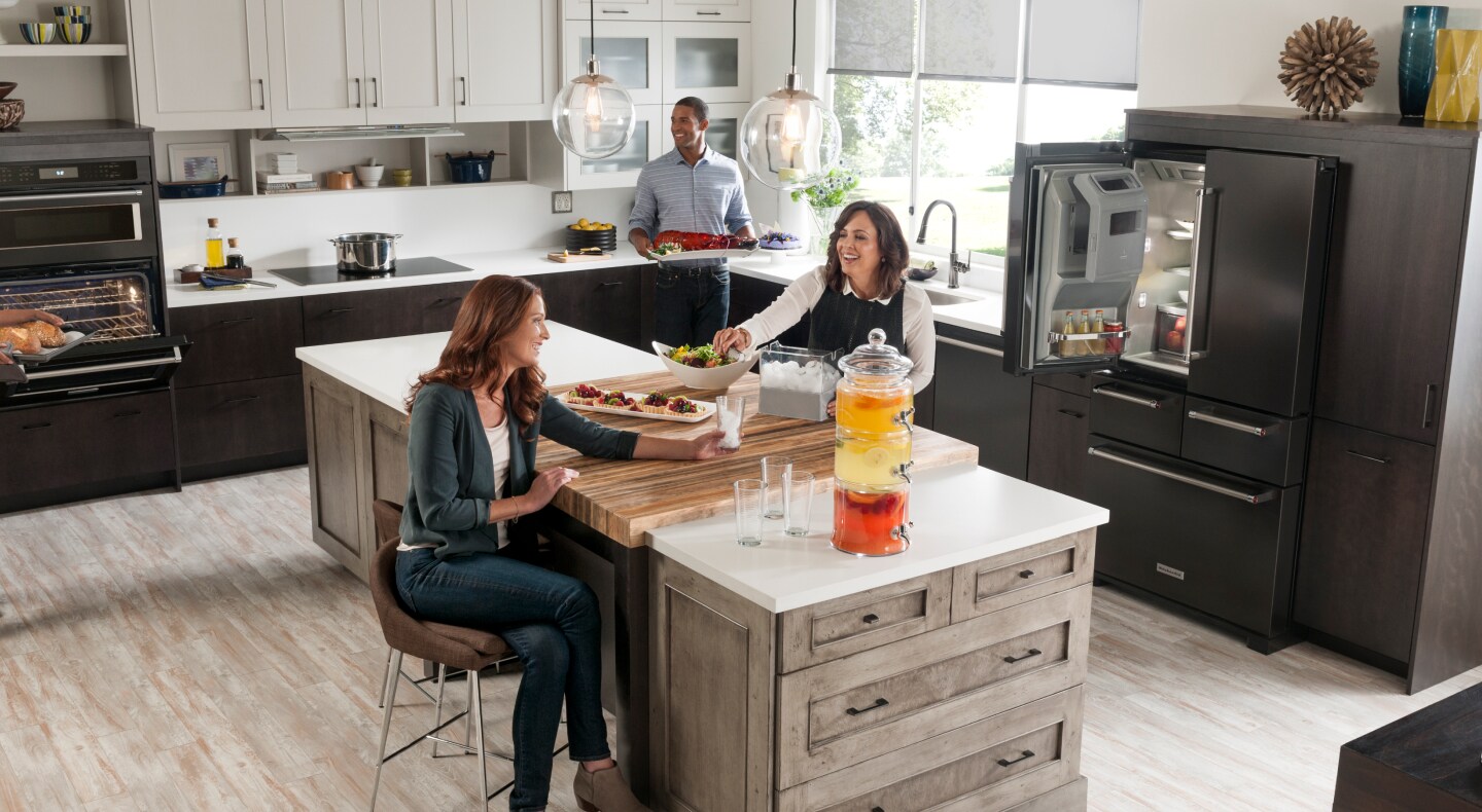 Friends gathered around a kitchen island in a contemporary kitchen Friends gathered around a kitchen island in a contemporary kitchen