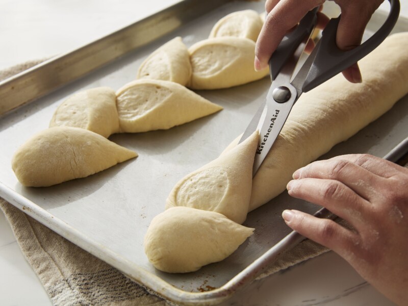 A person scoring bread with scissors A person scoring bread with scissors