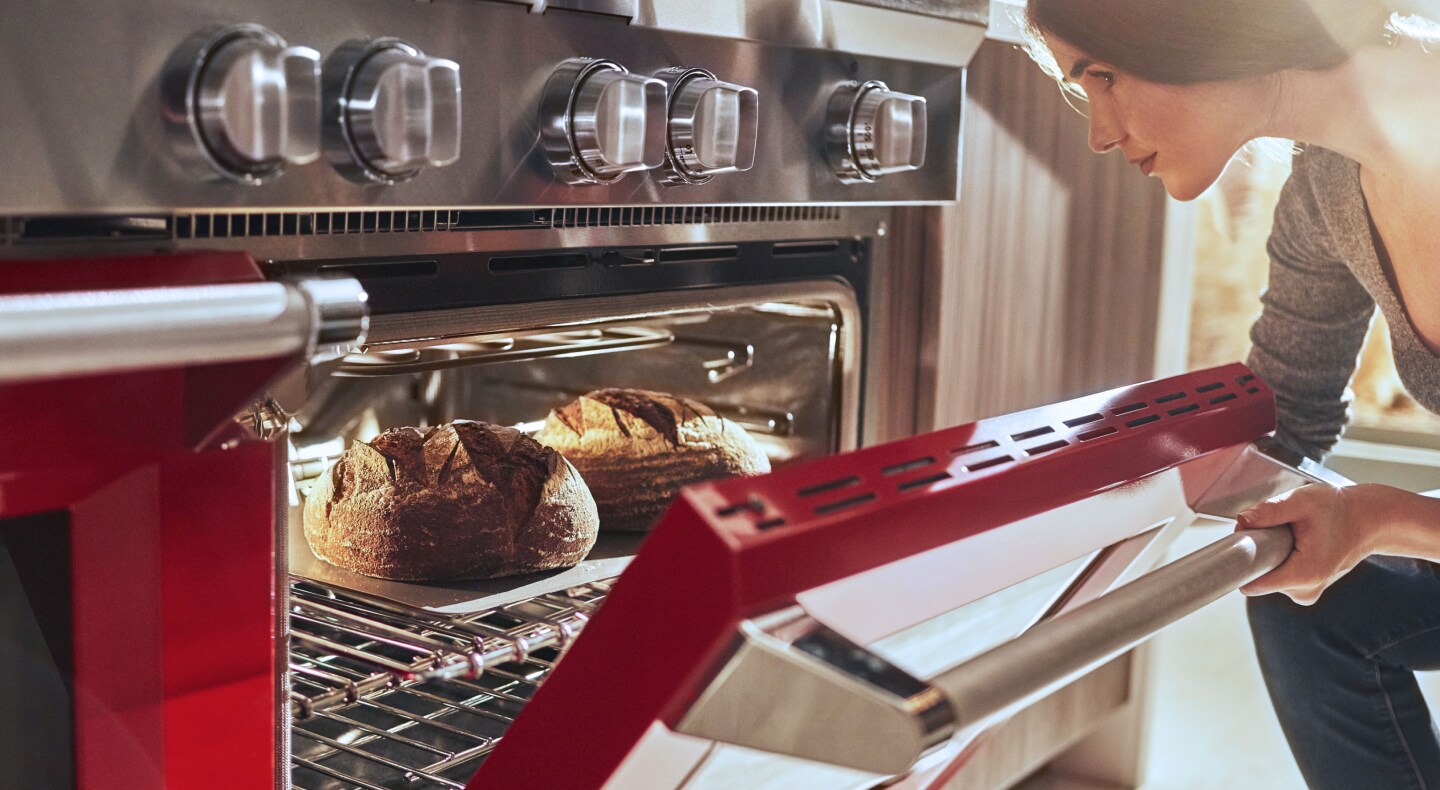 A woman pulling freshly baked bread out of an oven A woman pulling freshly baked bread out of an oven