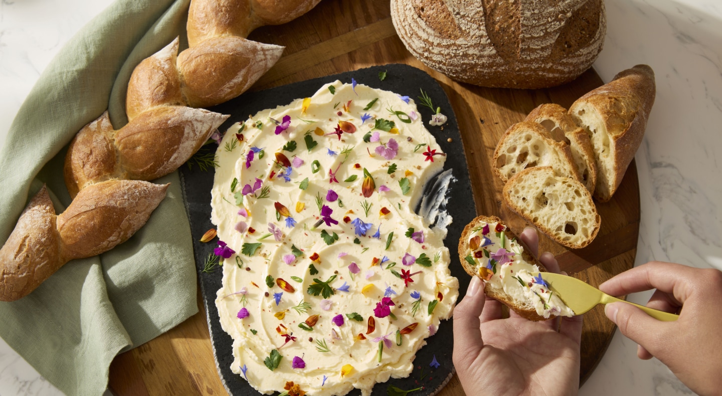 A person topping a loaf of baked bread with a homemade spread A person topping a loaf of baked bread with a homemade spread