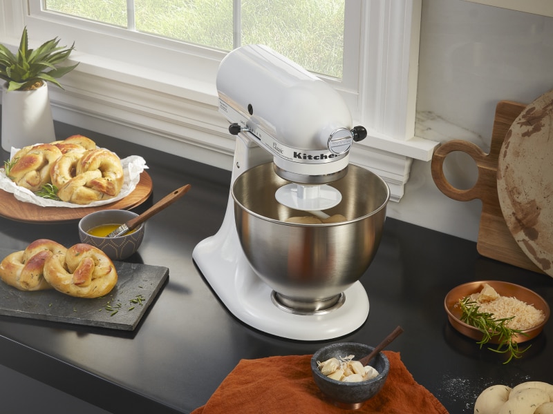 A stand mixer next to freshly baked pretzels