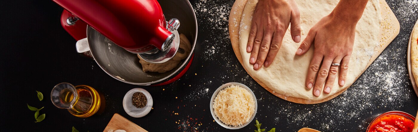 Person kneading stretching next to a KitchenAid® stand mixer