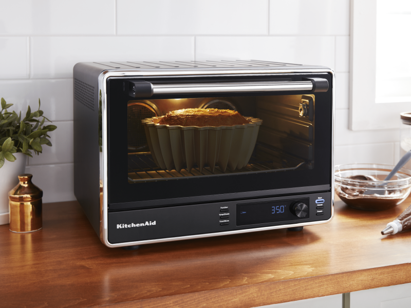 Black KitchenAid® countertop oven baking a bundt cake on brown countertop