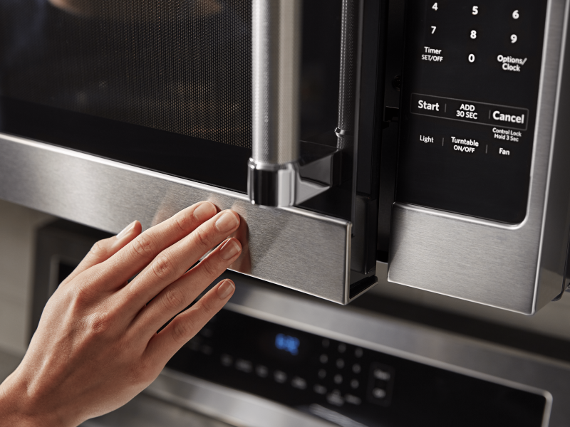 Person closing the door of an over-the-range microwave