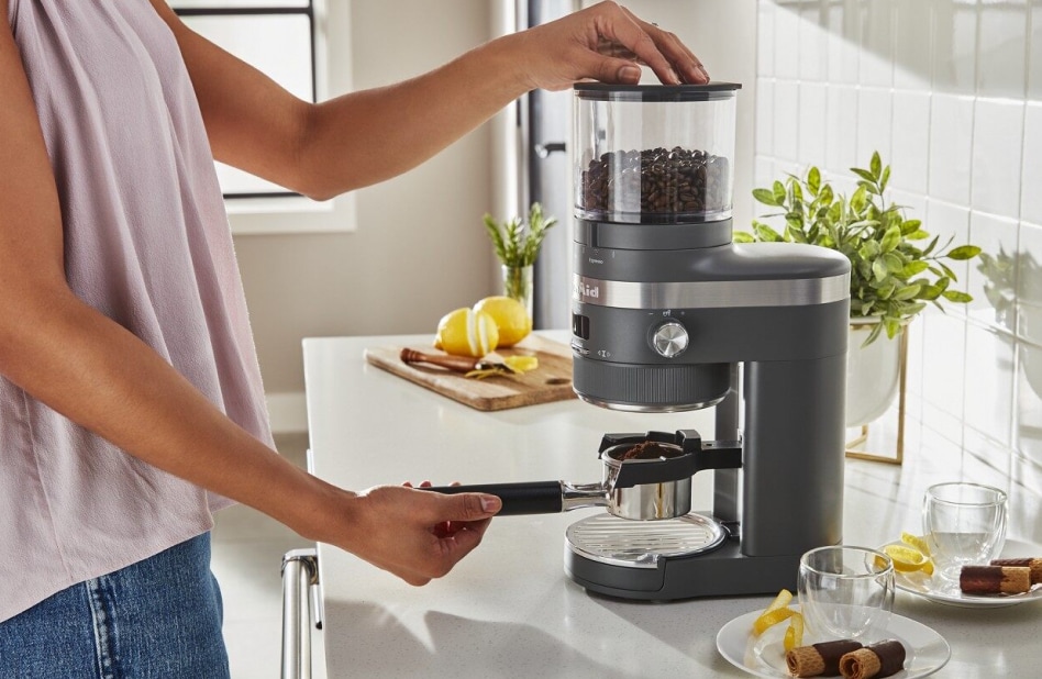 Hand placing portafilter under burr coffee grinder. Hand placing portafilter under burr coffee grinder.