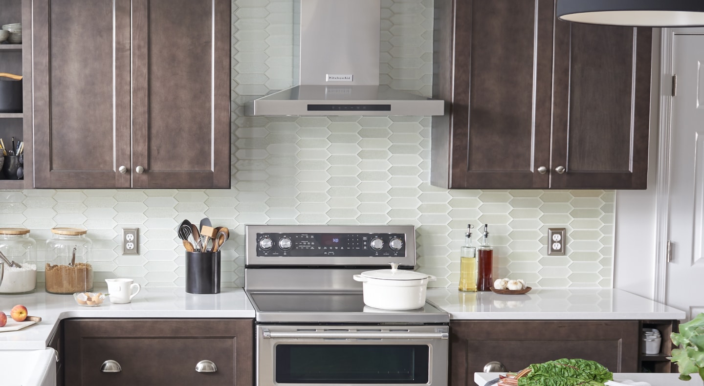 Wall-mount canopy hood between brown cabinets Wall-mount canopy hood between brown cabinets