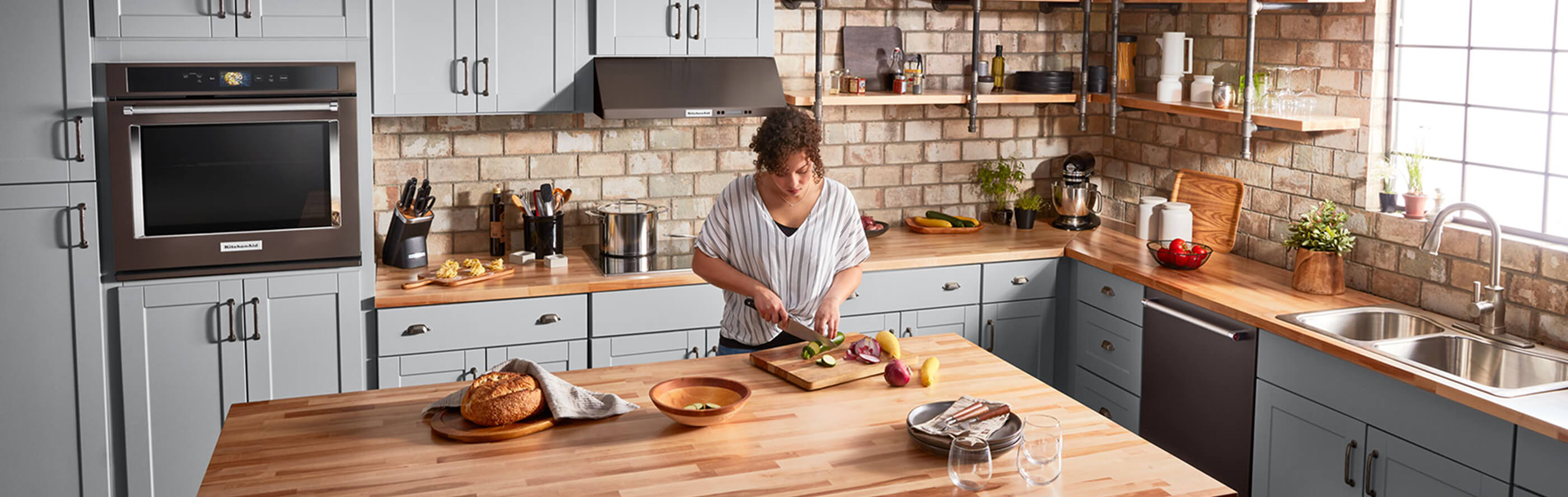 A person chopping vegetables at an island in a large, spacious kitchen