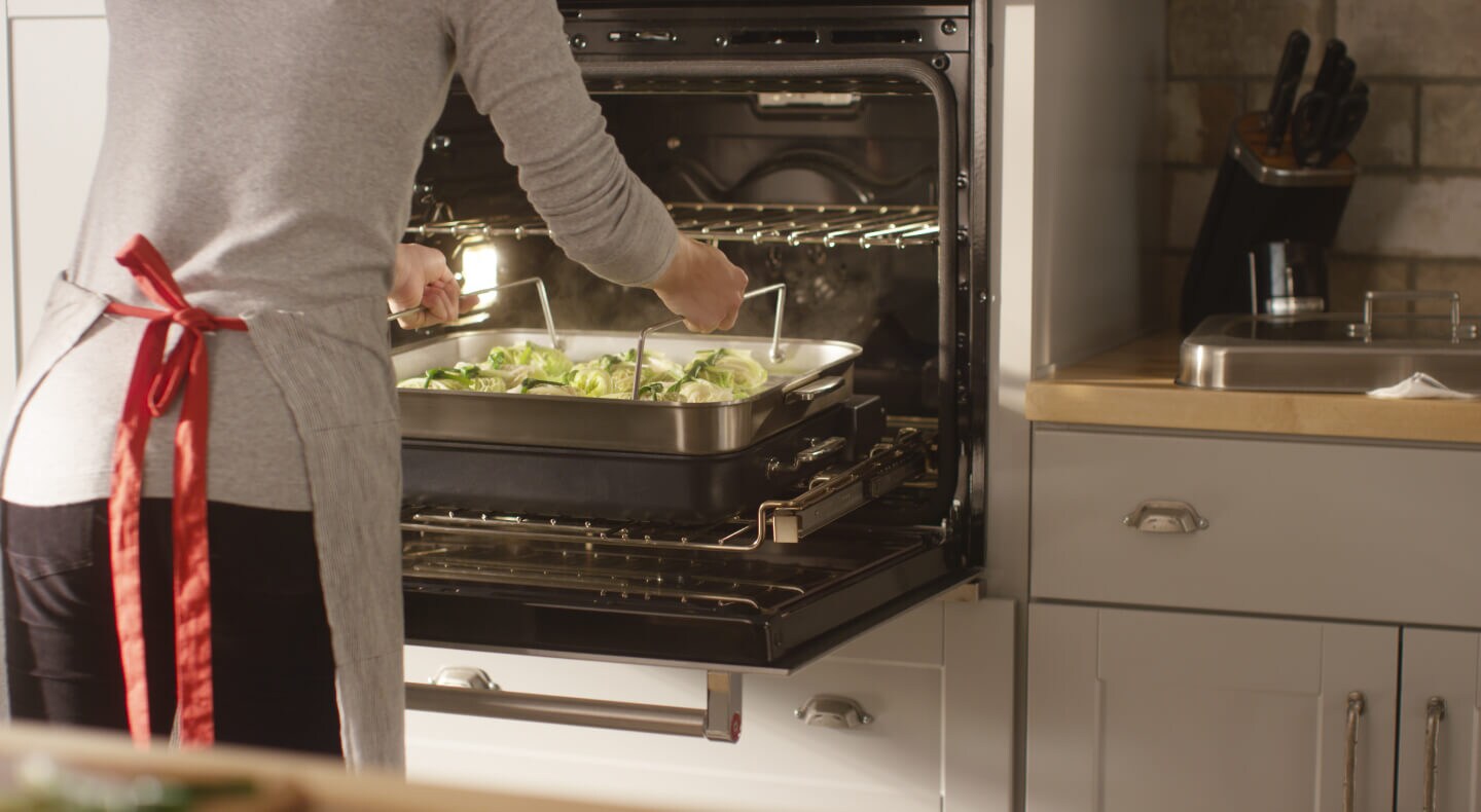 Person placing a baking dish of food in an oven
