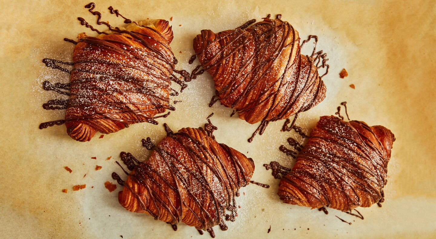 A set of eclairs with chocolate drizzled over them A set of eclairs with chocolate drizzled over them