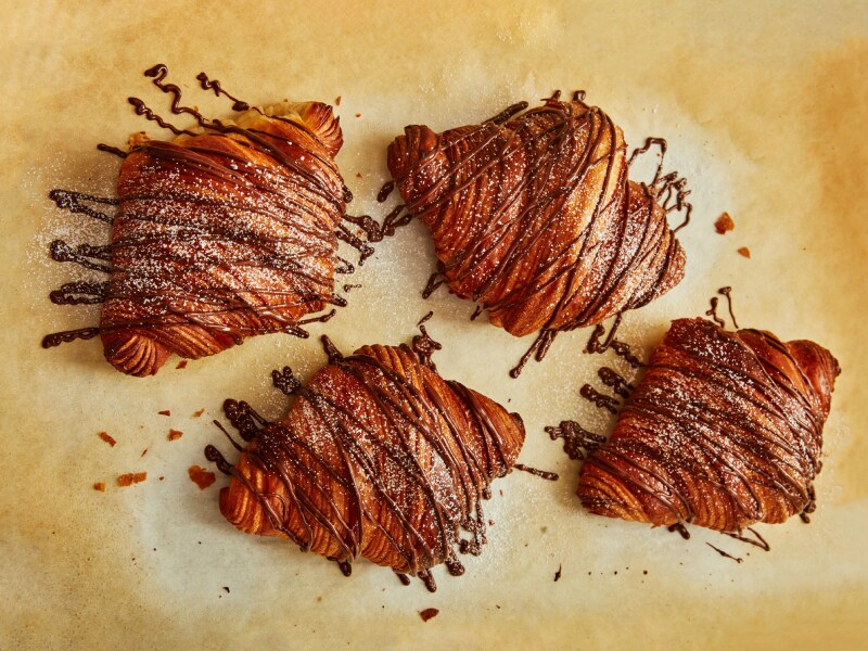 A set of eclairs with chocolate drizzled over them A set of eclairs with chocolate drizzled over them
