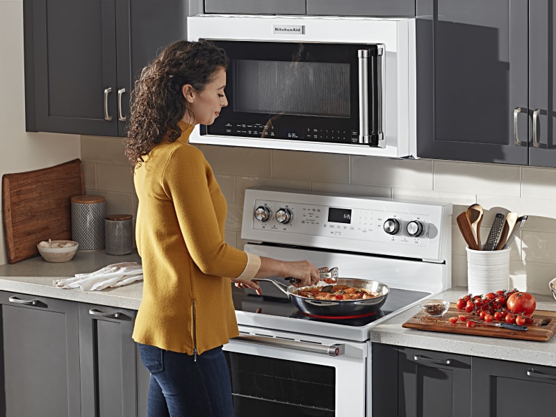 Person adding ingredients to a skillet on an electric stovetop Person adding ingredients to a skillet on an electric stovetop