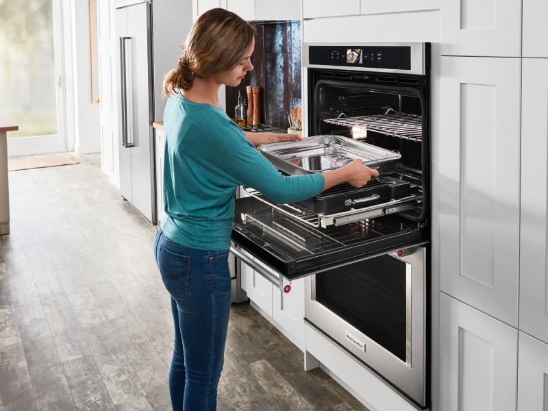 Woman removing baking sheet from the oven Woman removing baking sheet from the oven