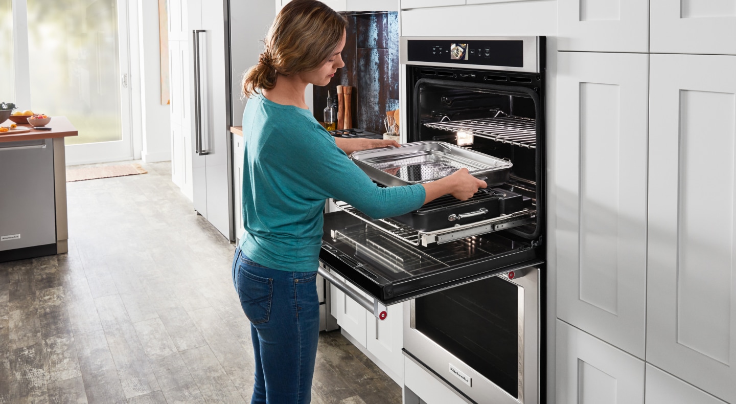 Woman removing baking sheet from the oven