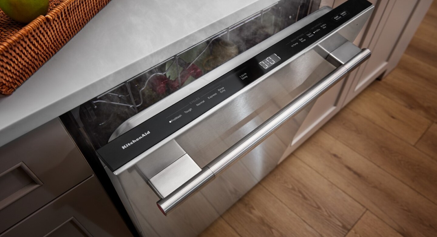 A built-in dishwasher with door slightly open to reveal top controls