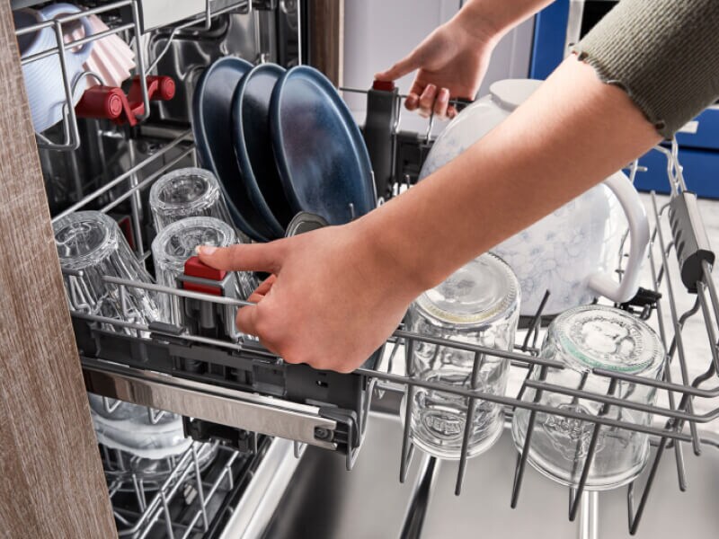 Dishwasher rack filled with clear glasses and blue plates