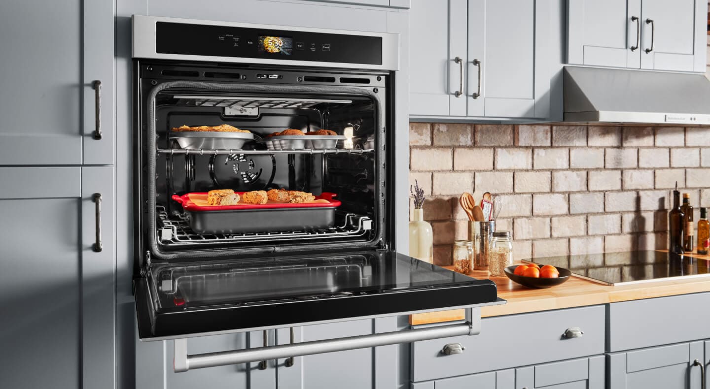 A pie, muffins and scones baking inside of a wall oven