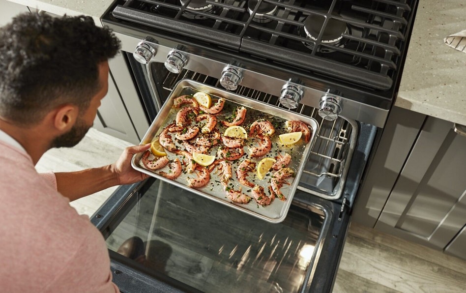Man pulling pan with shrimp out of convection oven Man pulling pan with shrimp out of convection oven