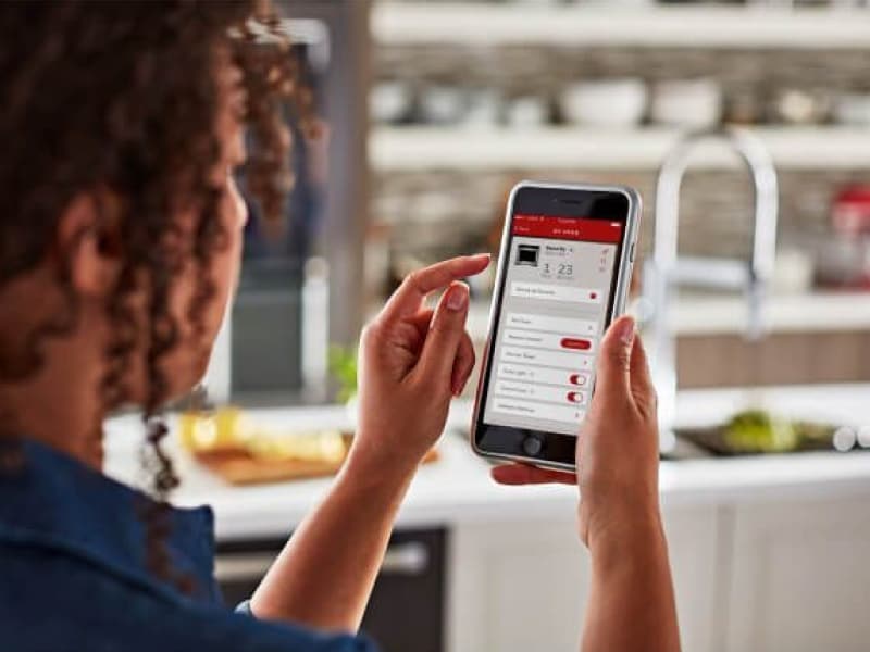 A woman using the KitchenAid® smart appliance app on a mobile device