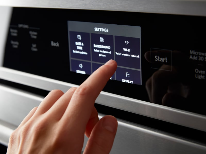 A person making a selection on the control pad of a smart oven