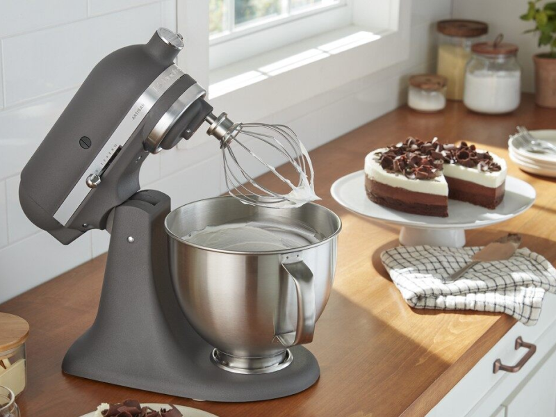 A black KitchenAid® stand mixer next to a cake on a counter. A black KitchenAid® stand mixer next to a cake on a counter.