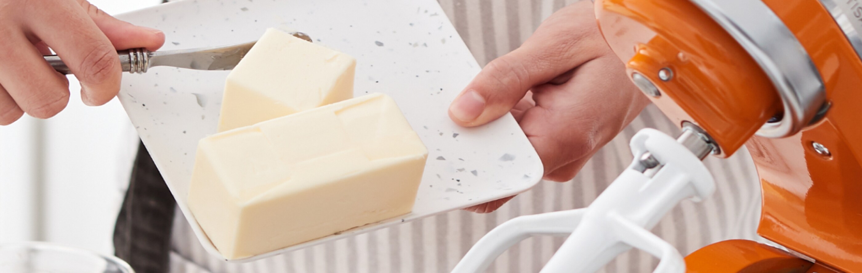 A person putting shortening in a stand mixer bowl