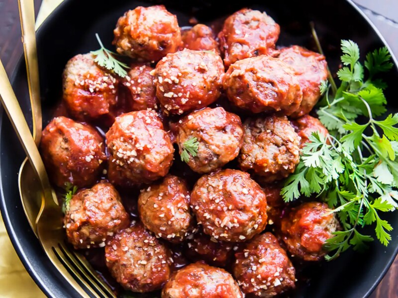 Birds-eye view of meatballs sprinkled with sesame seeds with cilantro on the side