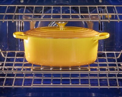 A yellow Dutch oven cooking inside of a KitchenAid® range