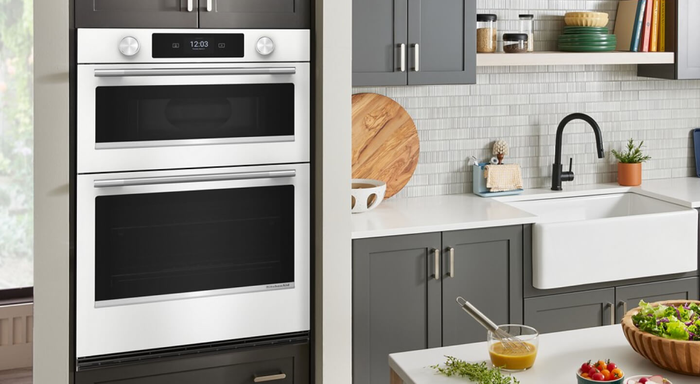 A kitchen with a white wall oven, sinks and coutnertops