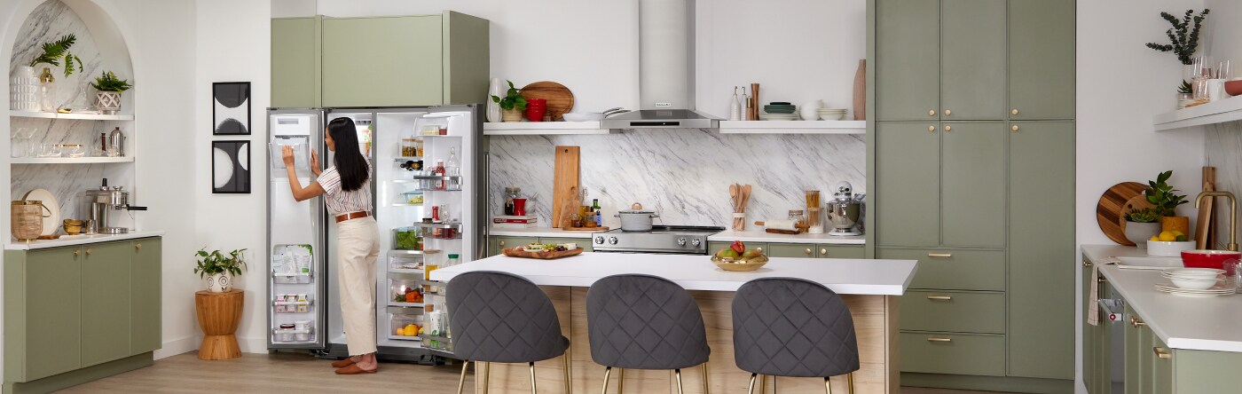 Person standing in front of an open refrigerator in a contemporary kitchen
