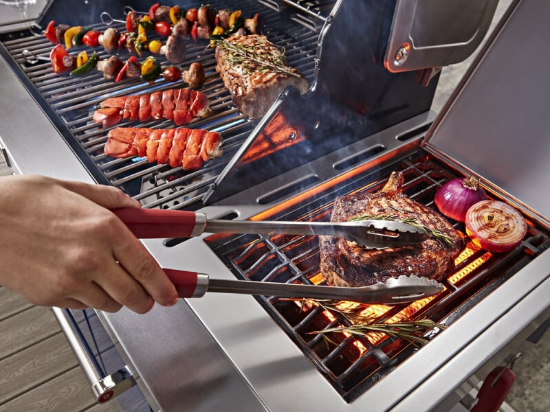 Person grilling steak and vegetables on an outdoor grill Person grilling steak and vegetables on an outdoor grill
