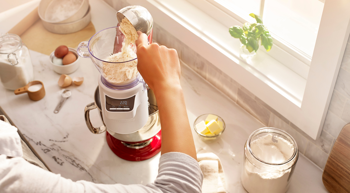 Person adding flour into a KitchenAid® stand mixer Person adding flour into a KitchenAid® stand mixer