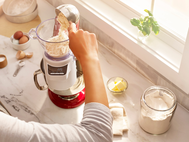 Person adding flour into a KitchenAid® stand mixer Person adding flour into a KitchenAid® stand mixer