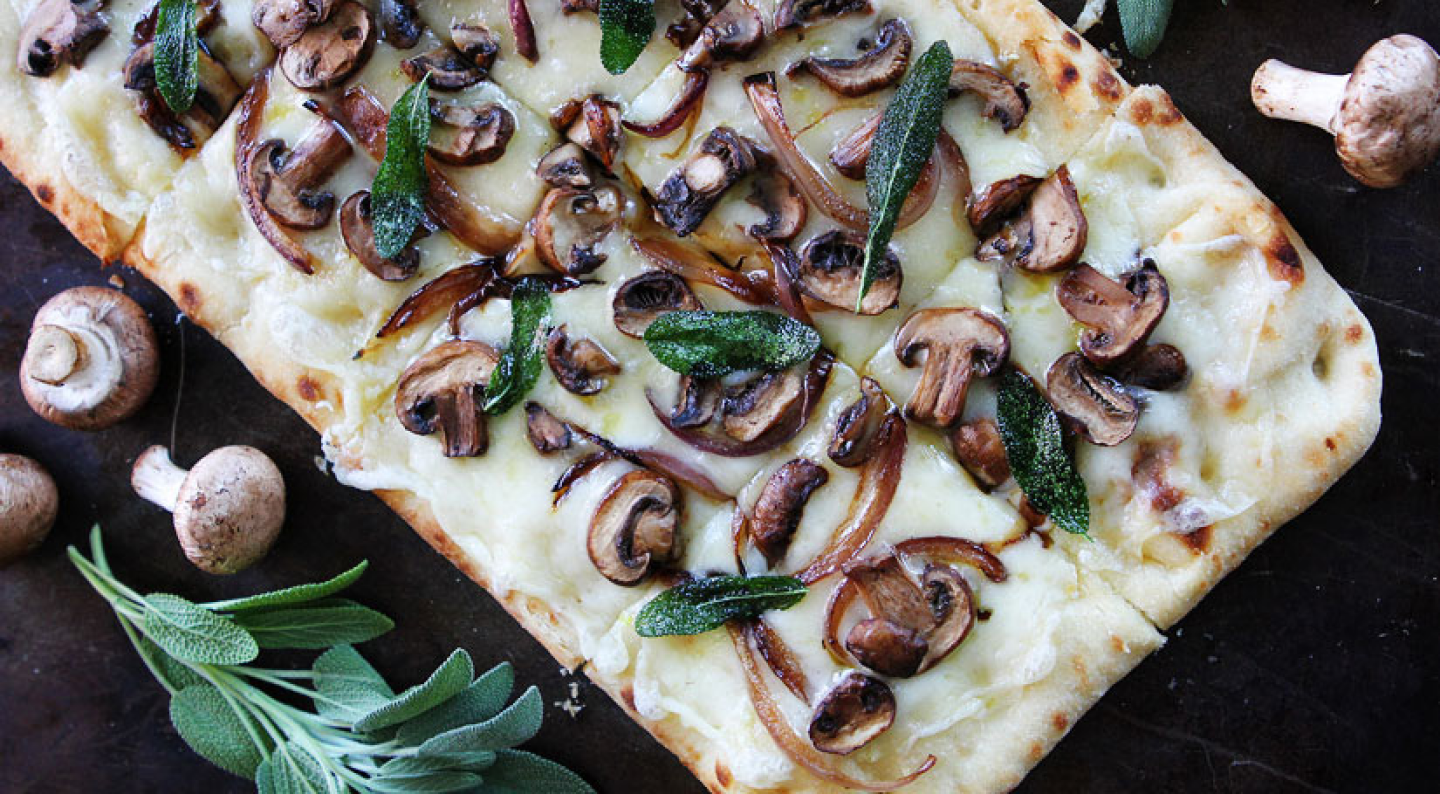 Flatbread pizza topped with cheese, mushrooms and herbs Flatbread pizza topped with cheese, mushrooms and herbs