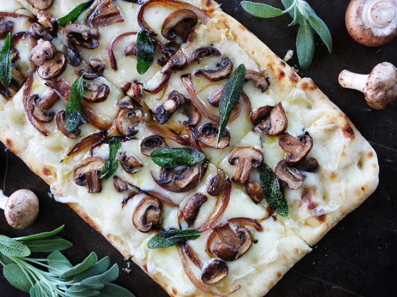 Flatbread pizza topped with cheese, mushrooms and herbs Flatbread pizza topped with cheese, mushrooms and herbs