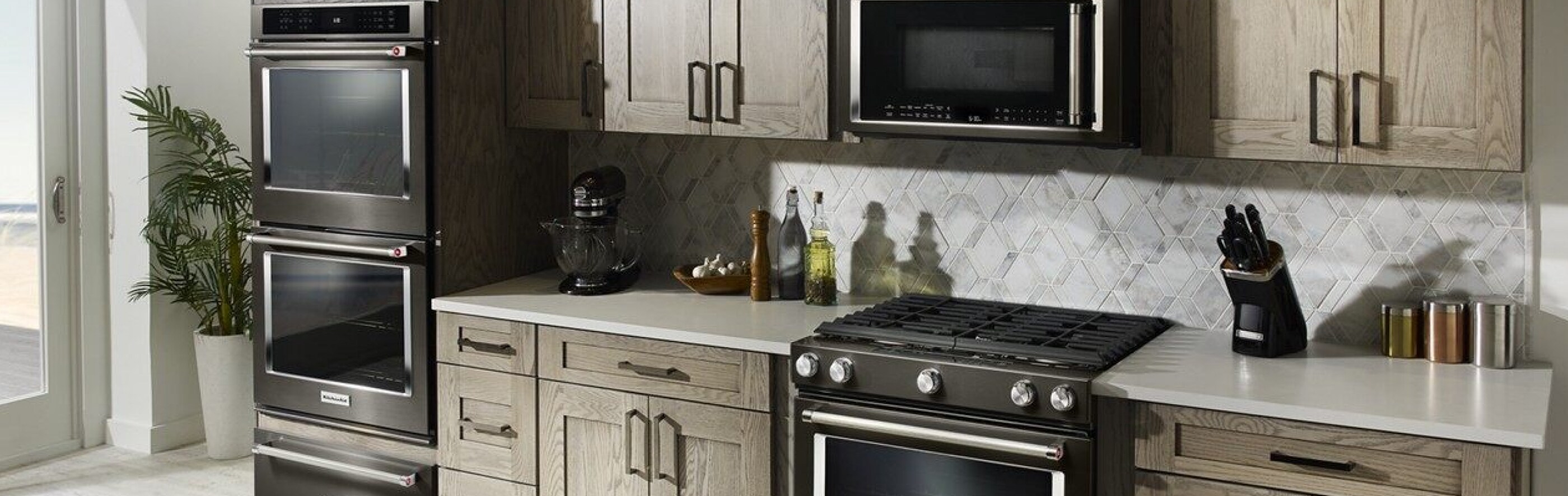 A black range, wall oven, microwave and warming drawer in a kitchen.